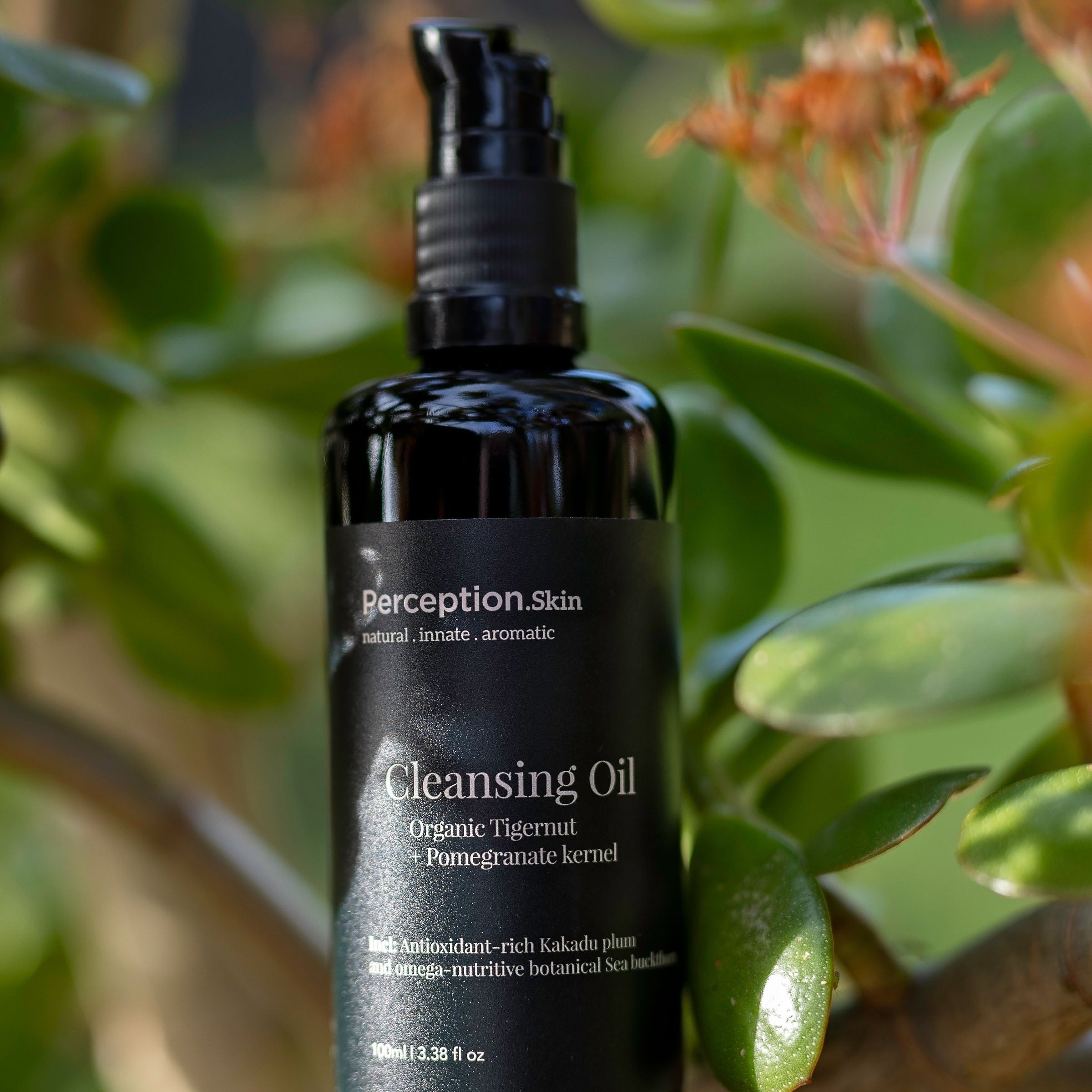 Perception Skin cleansing oil bottle on a branch with leaves and flowers in the background