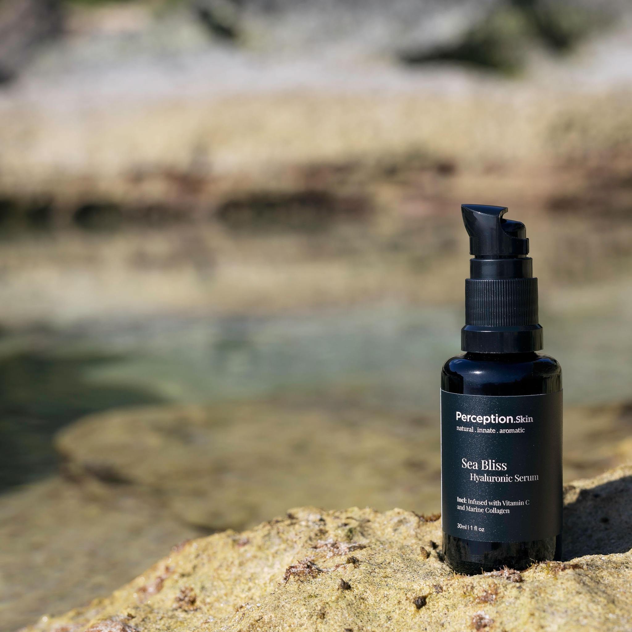 Perception Skin Sea Bliss Hyaluronic Serum bottle on a rock with water in the background