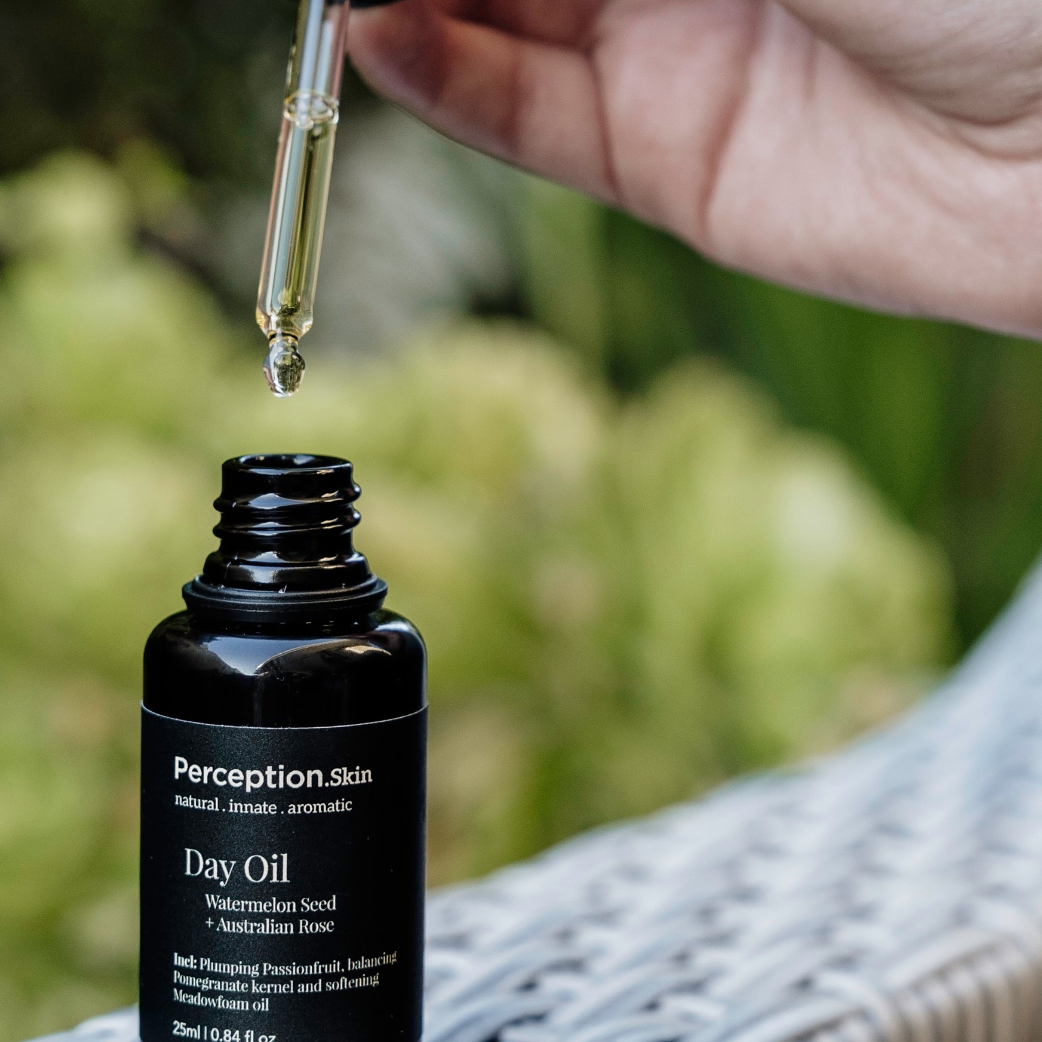 Clean + Conscious award-nominated Perception Skin's Watermelon Seed + Australian Rose Day oil being dropped into bottle on cane chair