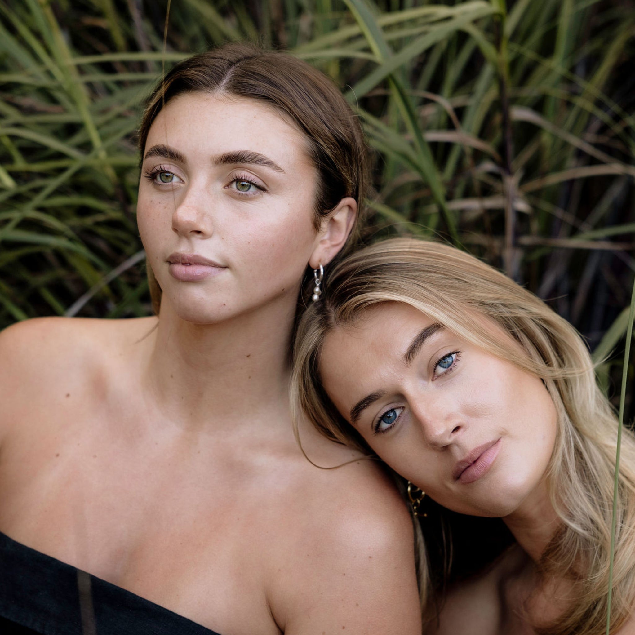 Two models promoting Perception Skin brand and ethos, sitting in nature with green reeds in the background