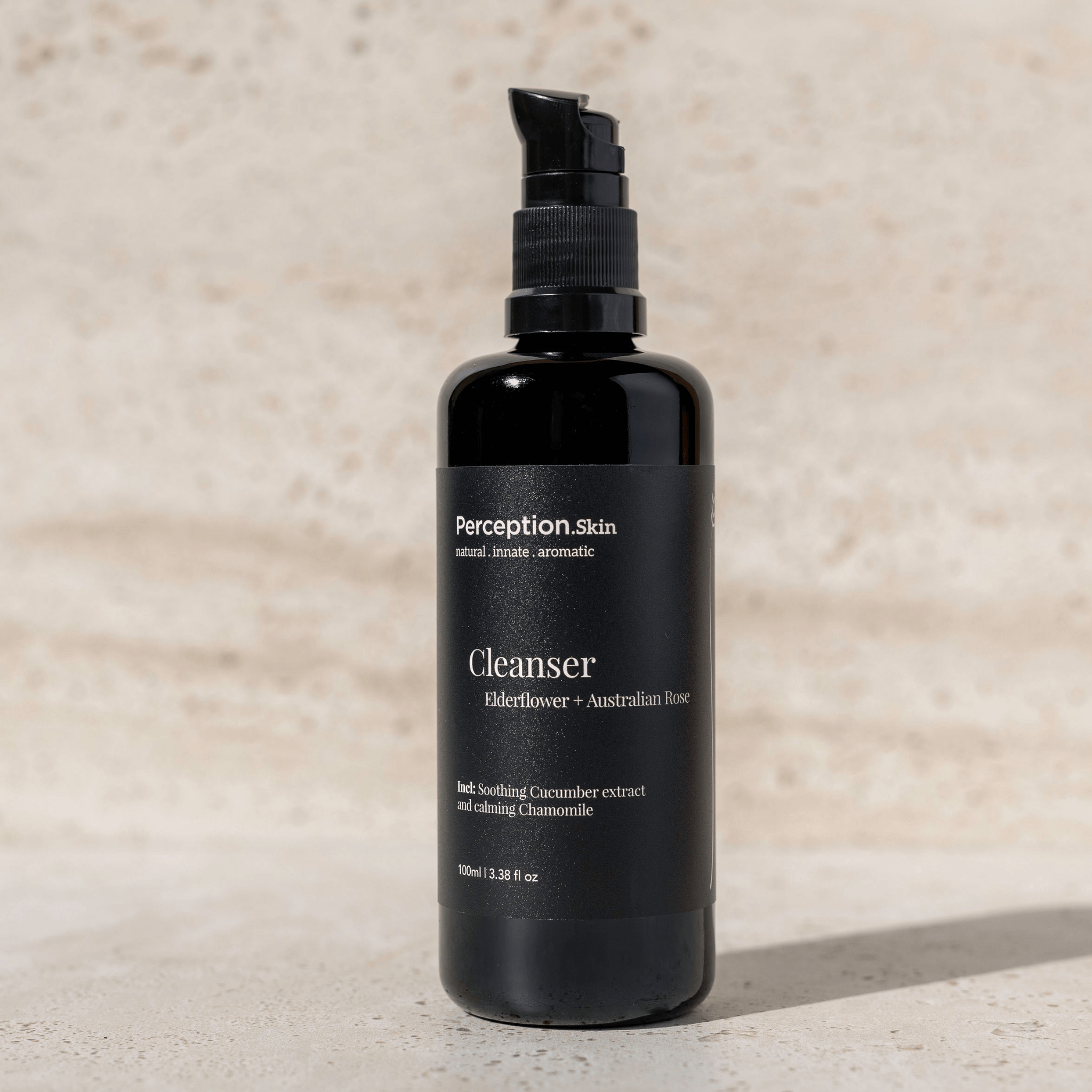 Black bottle of Perception Skin Cleanser on a beige background