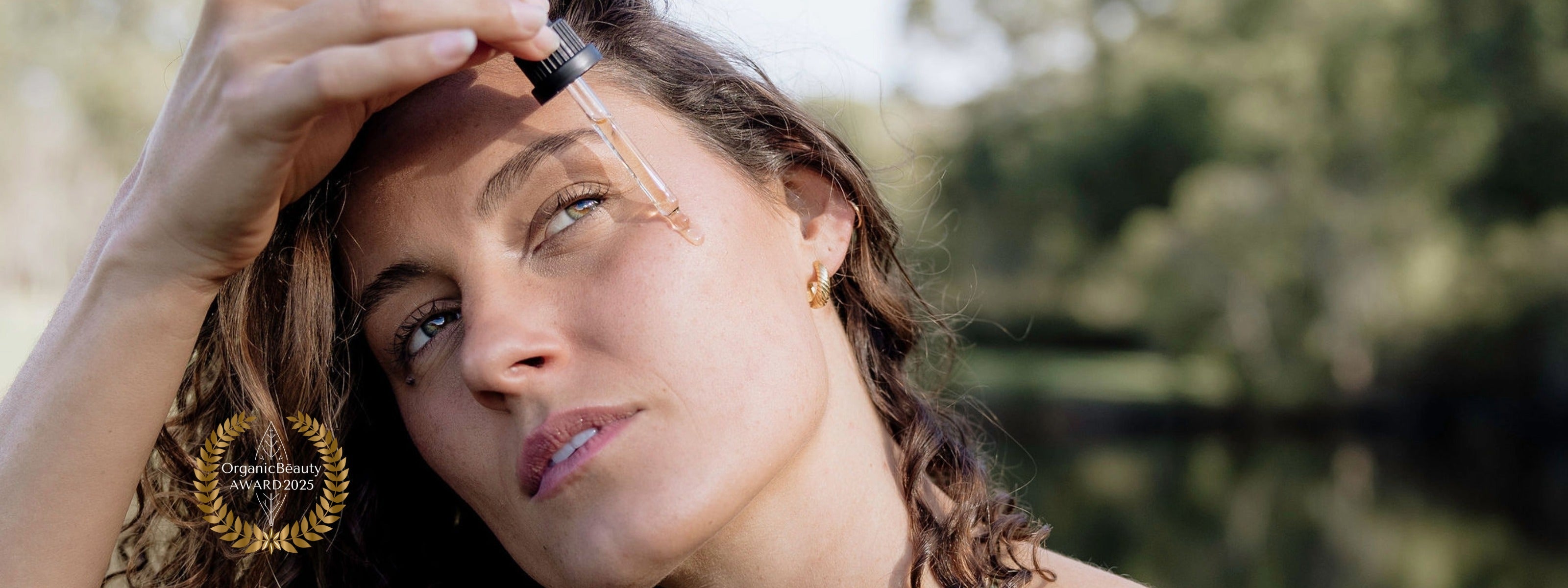 Model holding Perception Skin and dropping the Day Oil on her face.