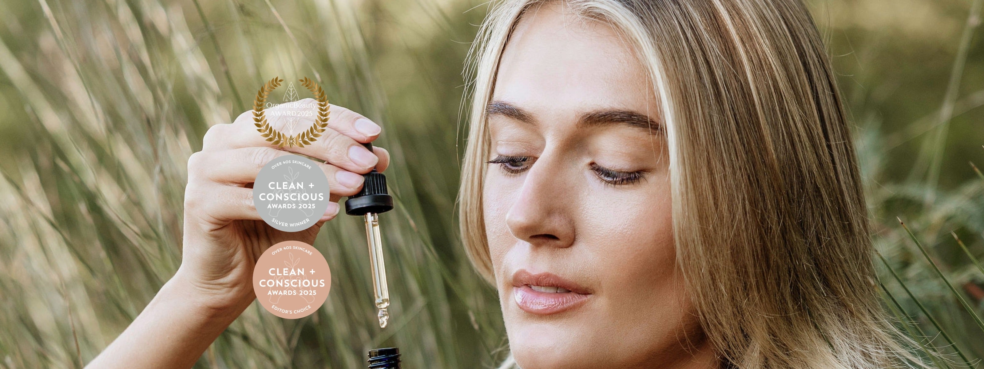 A woman outdoors in a grassy field holds Perception Skin Australian Native Day Oil.