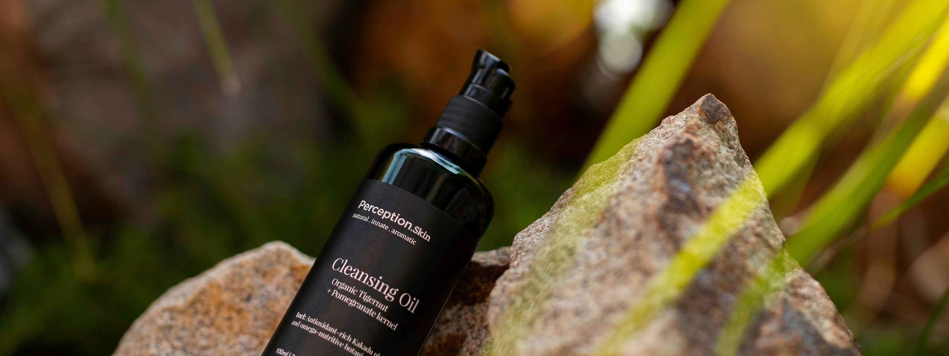 Perception Skin cleansing oil on a rock with grass in the background