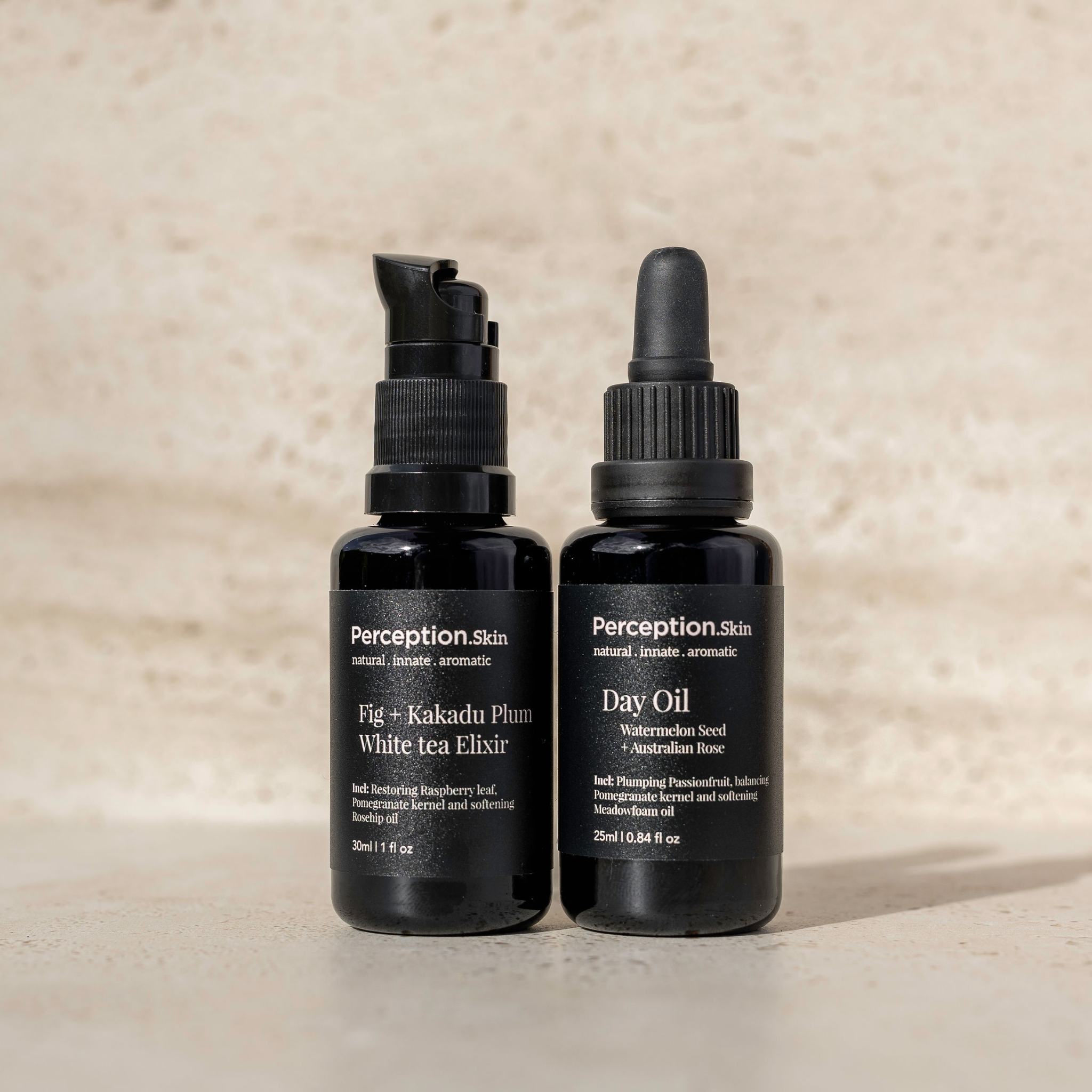 Two black skincare bottles labeled 'Fig + Kakadu Plum White Tea Elixir' and 'Day Oil' on a beige background.
