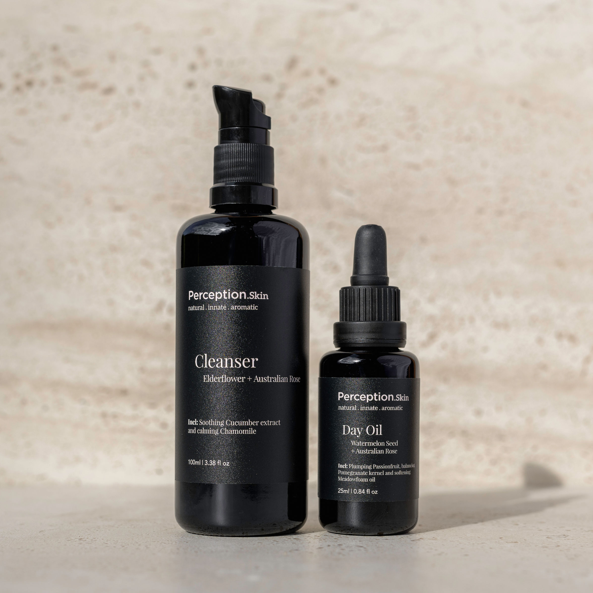 Two black skincare bottles labeled 'Cleanser' and 'Day Oil' on a beige background
