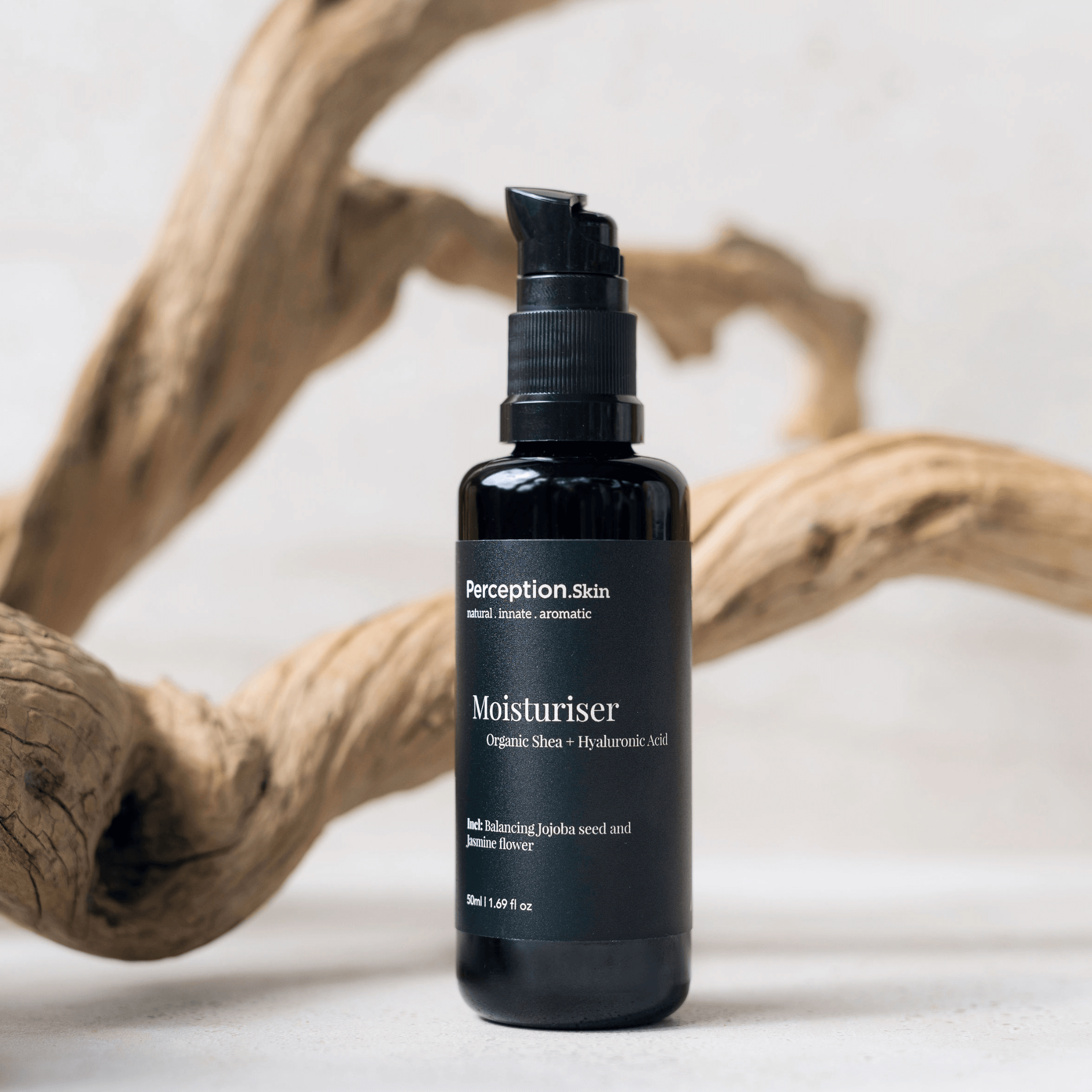 Black bottle of Perception Skins Moisturiser on a neutral background with wooden elements.