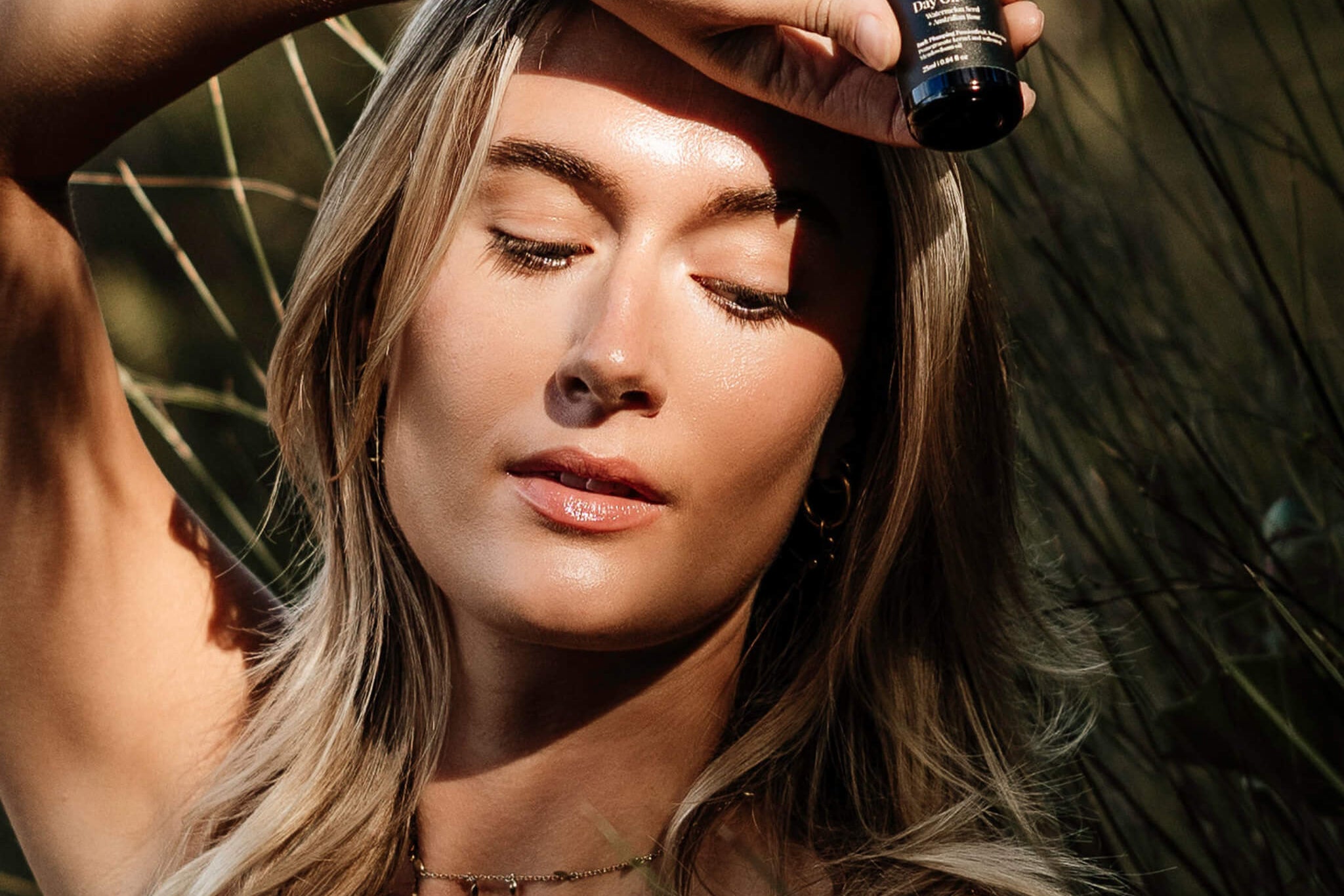 Woman holding a dropper bottle with a natural background