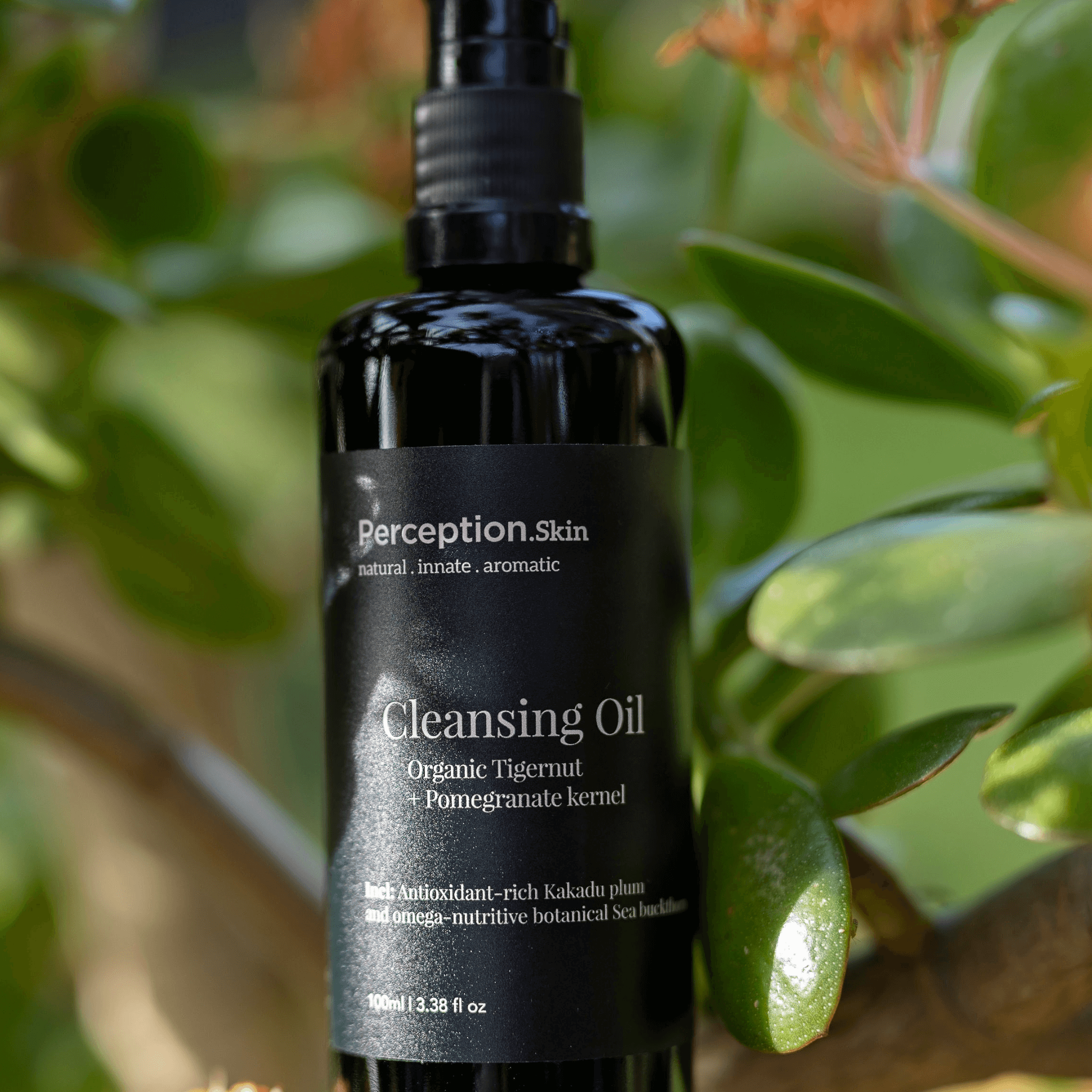 Black bottle of perception Skin Cleansing Oil with green leaves in the background