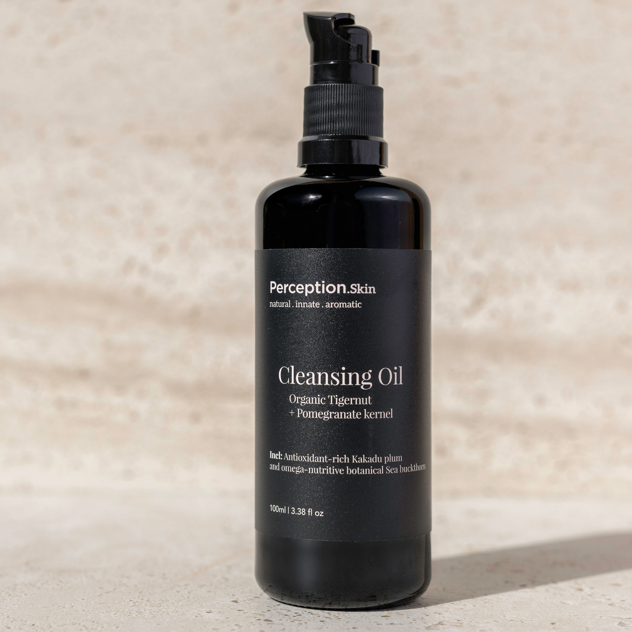 Black bottle of Perception Skin Cleansing Oil on a beige background