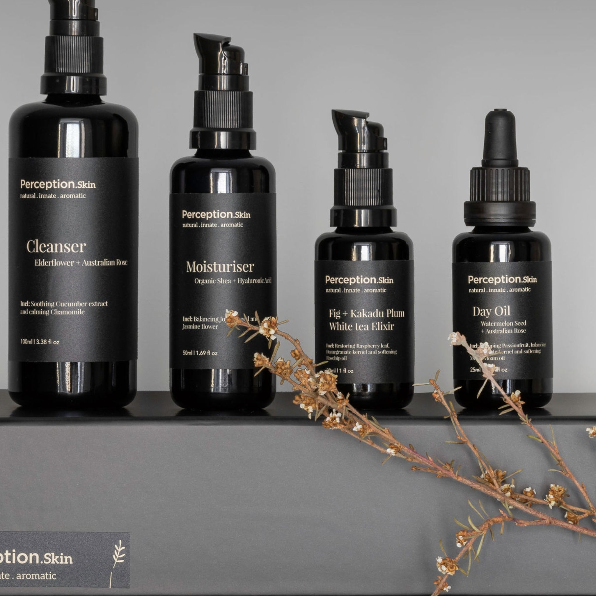 Set of Perception Skin skincare products on a gray background with dried flowers.